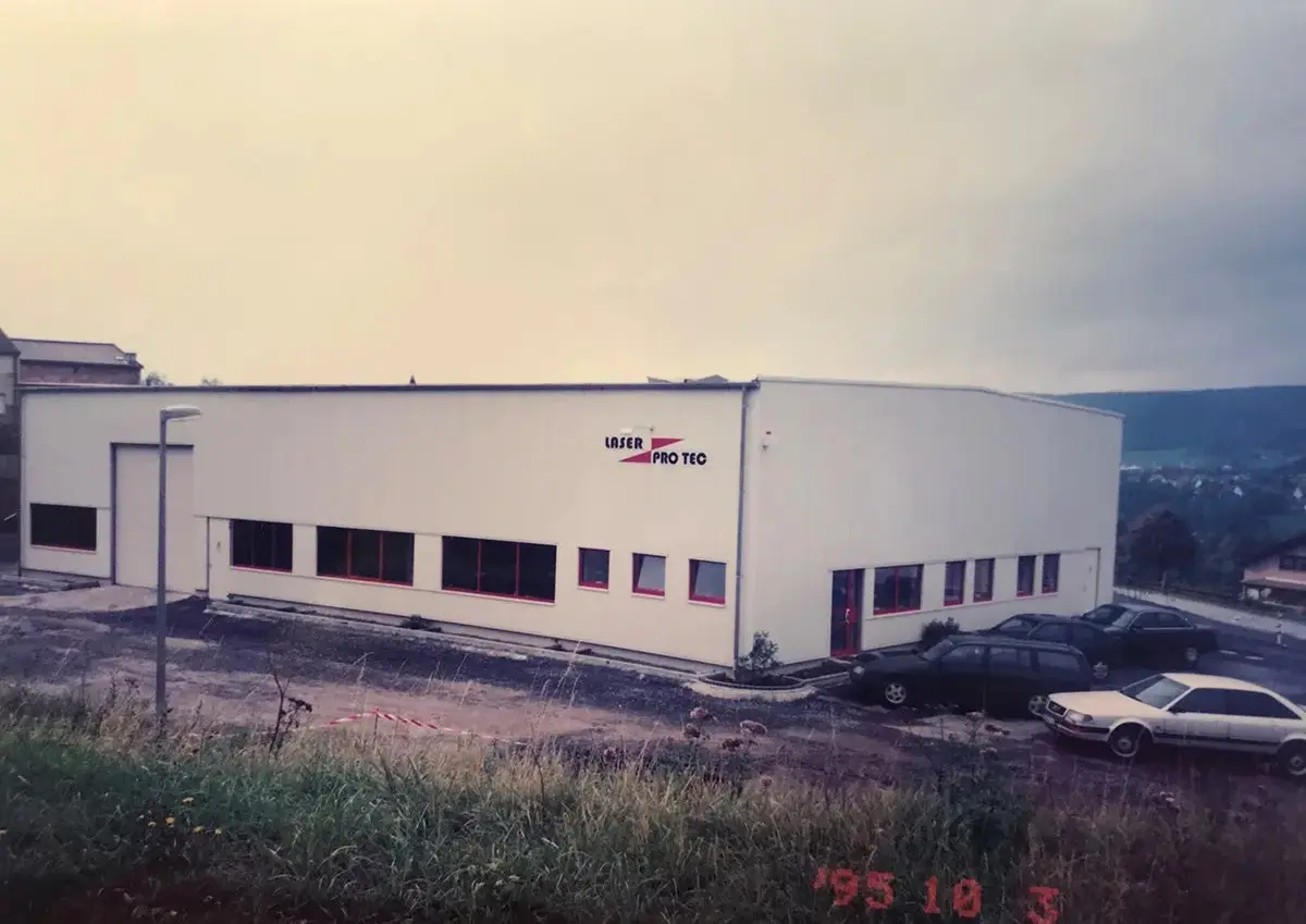 1995-1-jahr-nach-gruendung-laser-pro-tec-01 Fassade eines weißen Gebäudes mit dem Schriftzug 'Laser Pro Tec' im Jahr 1995.
