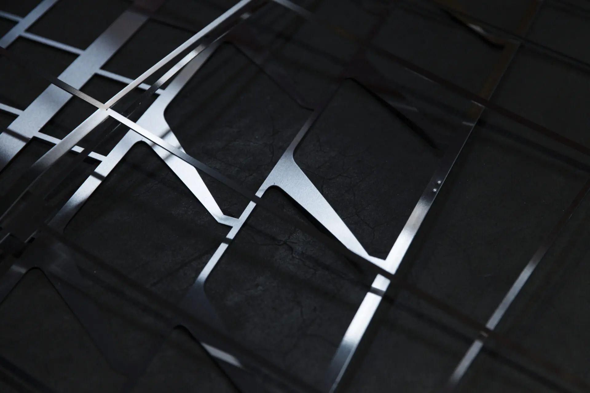 Laserbearbeitete Metallplatten mit geometrischen Mustern auf einer dunklen Oberfläche.