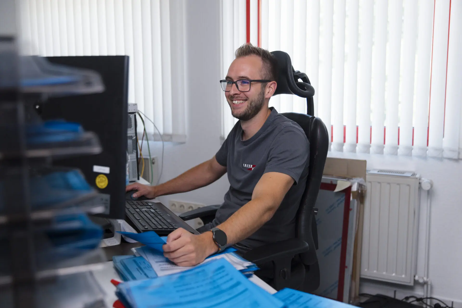 Ein Mann sitzt an einem Schreibtisch und arbeitet an einem Computer in einem Büro.