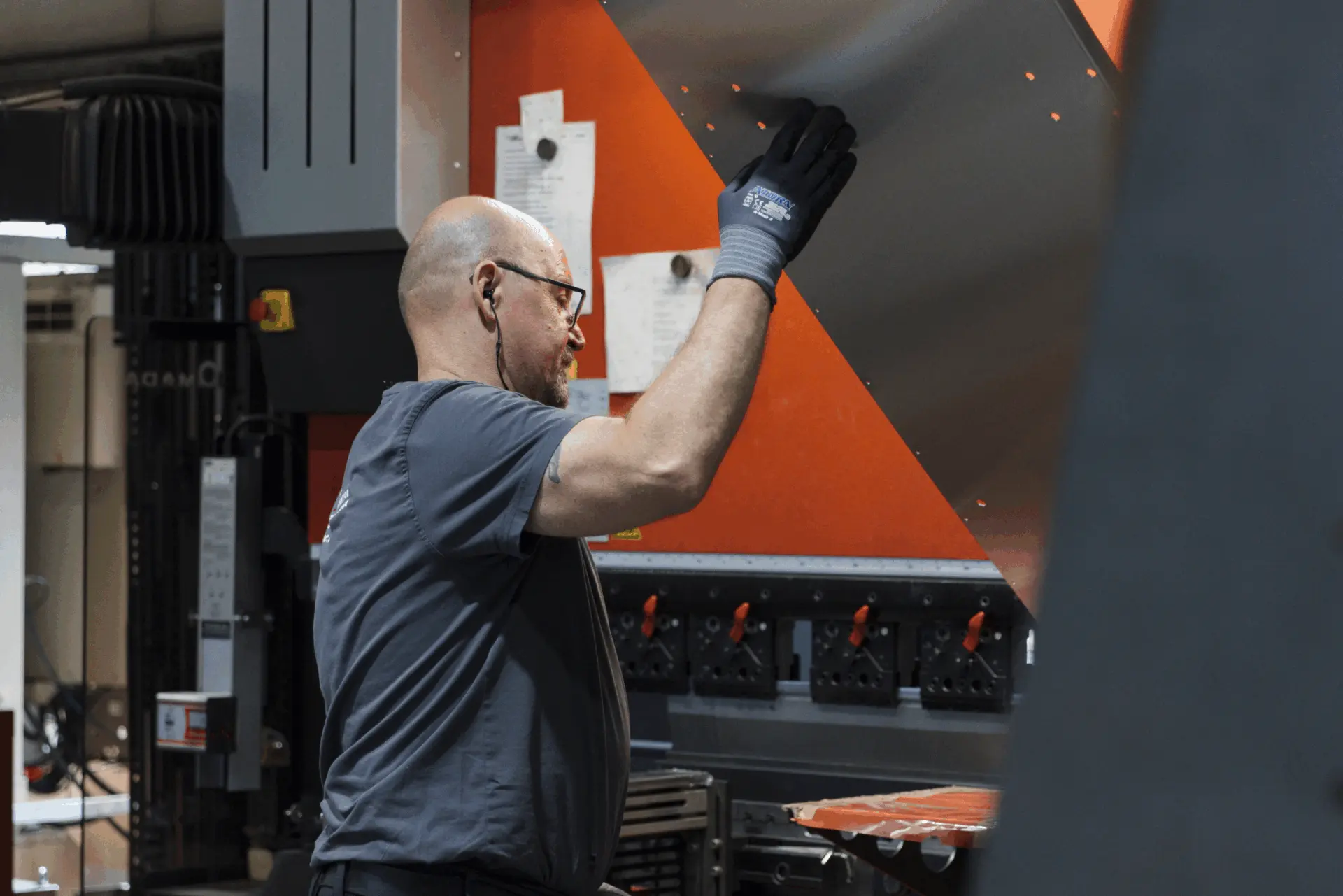 Arbeiter in einer Fabrik, der ein Blech an einer Blechbiegemaschine bearbeitet.